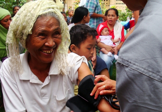 Doctor checks an elderly woman's eyes in Southeast Asian Muslim village